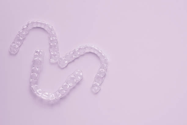istock Invisible dental teeth brackets tooth aligners on pink background. Plastic braces dentistry retainers to straighten teeth. 1307030062