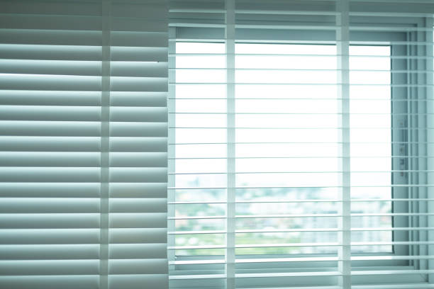 istock Sunlight coming through white venetian blinds in home 1307030437