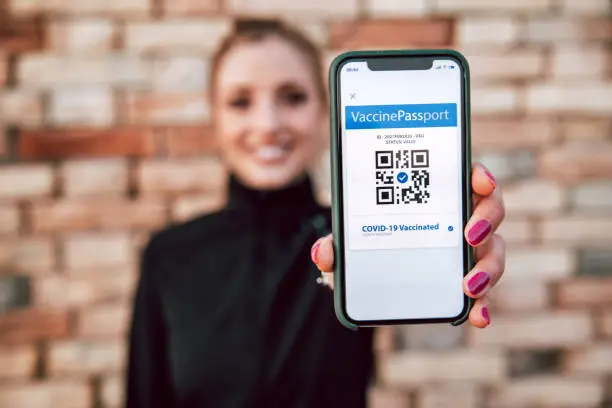 Young woman showing on mobile app her Covid-19 vaccination Passport