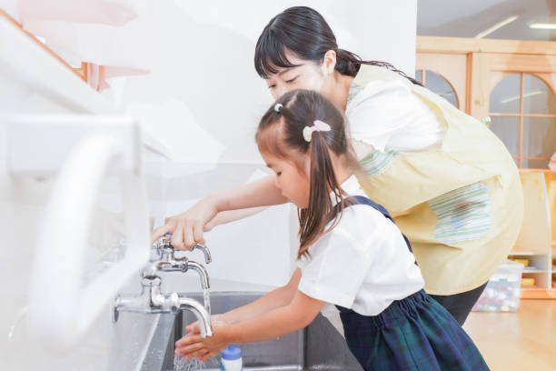 istock Girl and teacher washing hands 1307035661