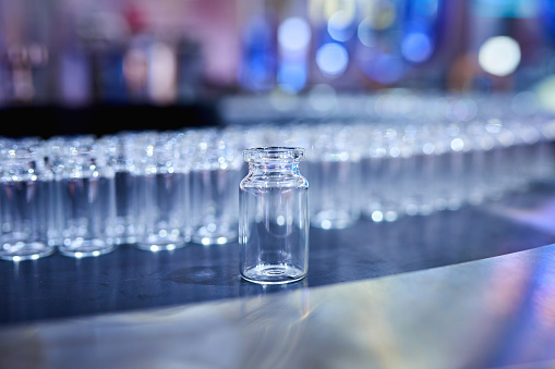 Foreground focus of transparent glass bottle at production line.