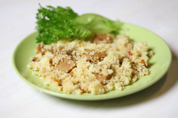 istock Cuscus with carrot, tomato, pork and salad leaf on green plate on white table 1307042743