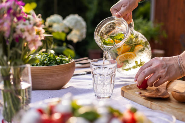 frau gießt trinkwasser ins glas - superfood food healthy eating healthy lifestyle stock-fotos und bilder
