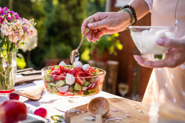 donna che mette la mozzarella all'insalata di verdure - salad food caprese salad gourmet foto e immagini stock