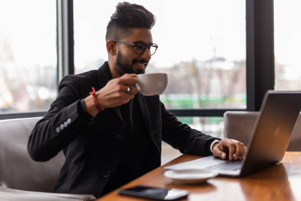 istock Indian Businessman Using Phone Whilst Working In Coffee Shop 1307045577