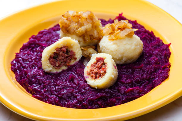 potato dumplings filled with smoked meat with fried onion on red cabbage