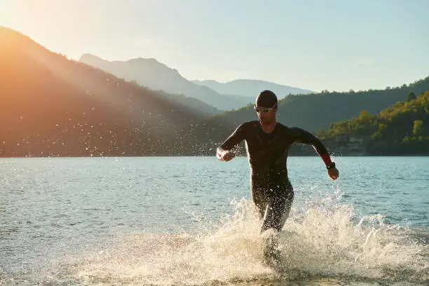 triathlon athlete start swimming training splashing water while running and jumping