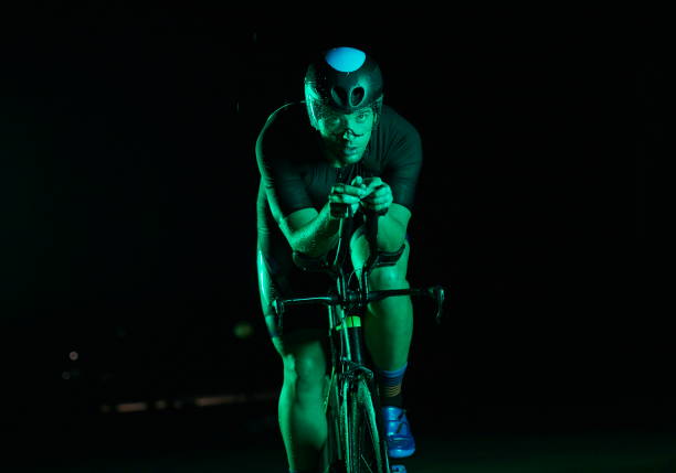 istock triathlon athlete riding bike fast at night 1307046656