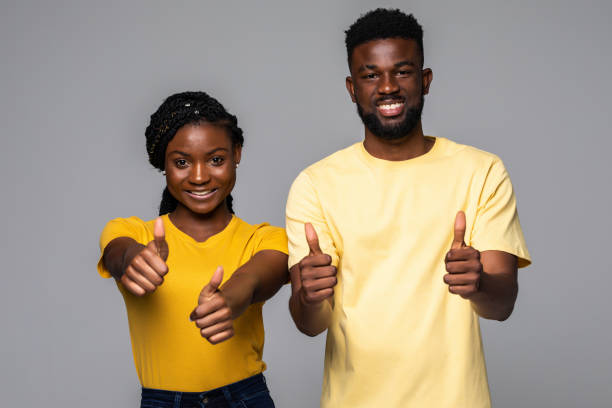 istock Overjoyed African couple showing thumbs up gesture isolated on gray studio background, 1307046901