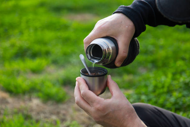 istock Enjoying coffee with thermos in the outdoors. Green grass in background, horizontal. 1307047048