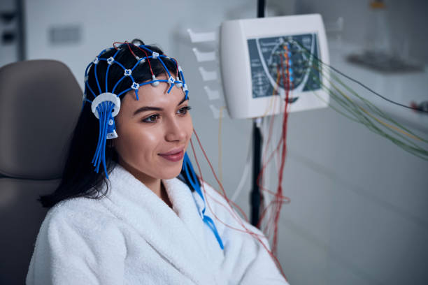 Pleased female patient undergoing an EEG test Smiling young woman with a silicone cap on her head dreaming away during the electroencephalography eeg stock pictures, royalty-free photos & images