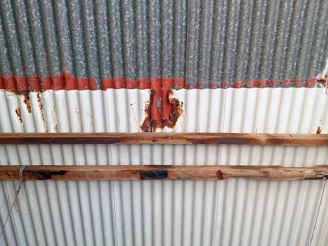 Rusty sheet metal roof with corrugated sheets and wooden beams. Zinc plate rust. Rusty metal background with streaks of rust. Interior carpentry ceiling in the FWI. Interiors, construction pattern.