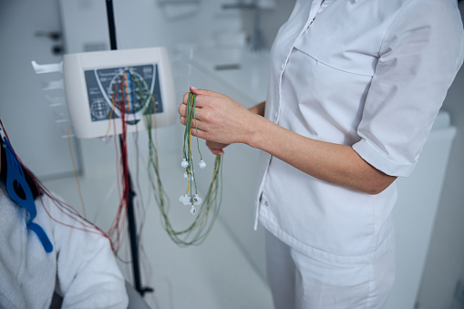 Cropped photo of an experienced neurophysiologist in a lab coat holding the electrodes in her hands