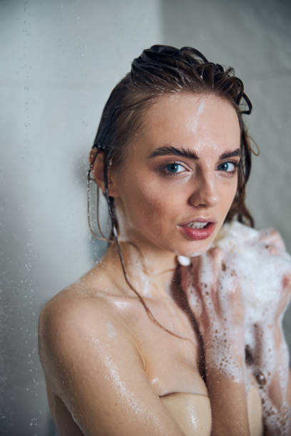 istock Young lady with a soapy bath sponge gazing ahead 1307050844