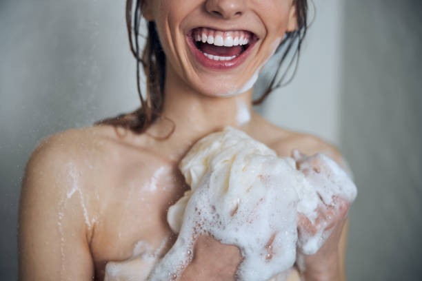 istock High-spirited young female using a bath sponge in the shower 1307050905