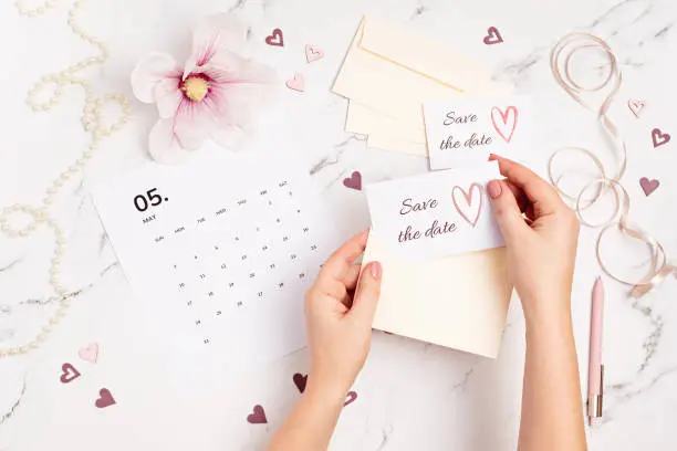 Photo of Woman hands putting save the date card in the envelope. Wedding planning, invitation concept