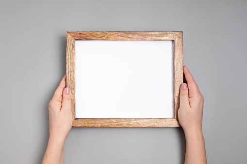 Woman hands holding blank wooden frame . Mockup, template, copy space