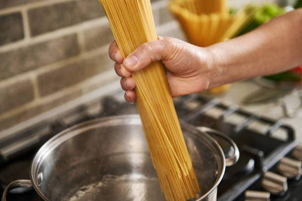 istock Close-up of hands holding spaghetti and throwing them into boiled water 1307054204