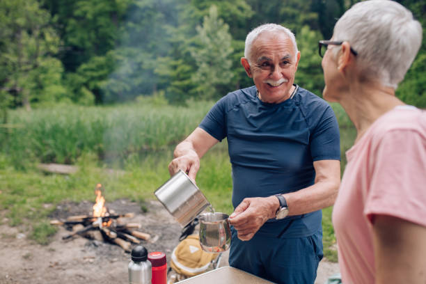istock Happy senior man making tea for him and his wife during camping 1307057837