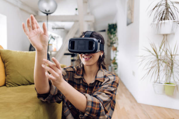 istock Young woman playing with a virtual reality headset at home 1307058352