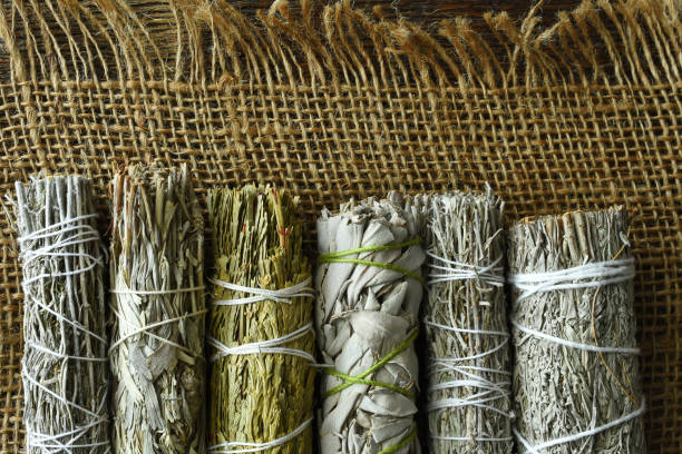 White Sage Smudge Bundles A top view image of several healing sage smudge bundles on burlap fabric. smudged stock pictures, royalty-free photos & images