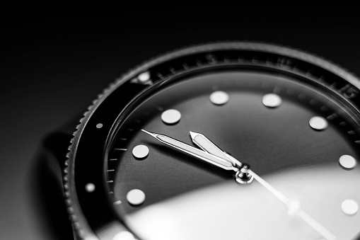 Black and white photo of silver, pocket watches. Clock - time on a wooden table. On the table are an open karman clock on a chain. Pocket watch made of silver on a chain. Open pocket watch.