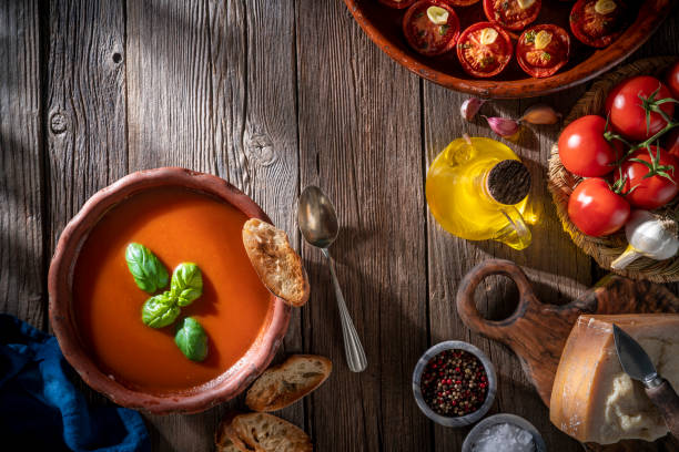 istock Tomato soup with roasted tomatoes, basil, ingredients  and toasted bread on rustic wood 1307061939