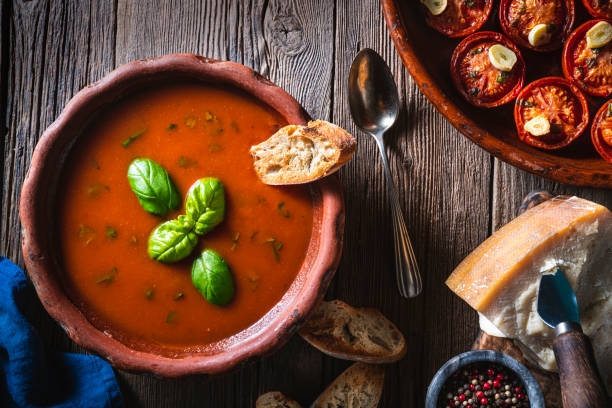 istock Tomato soup with roasted tomatoes, basil, ingredients  and toasted bread on rustic wood 1307061970