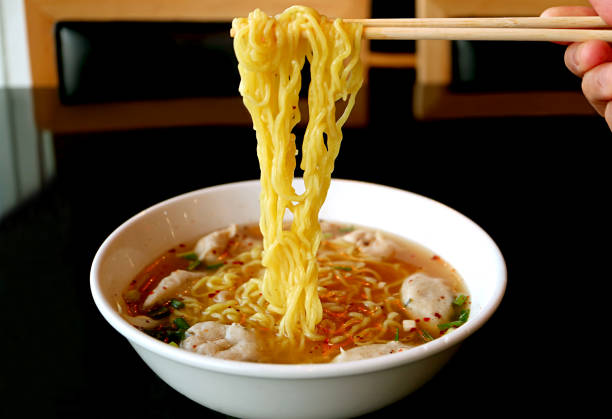 istock Hand Grabbing Thai Egg Noodles with Assorted Fish Balls in Spicy Soup 1307062790