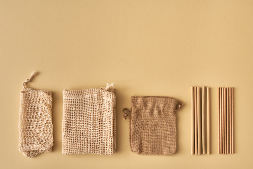 Mesh bags made of organic cotton, linen sac, bamboo and paper straws - ecological zero-waste concept with copy space