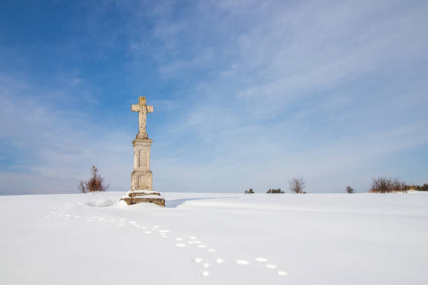 A detailed carving of Jesus Christ is blanketed in snow, creating a serene and peaceful scene