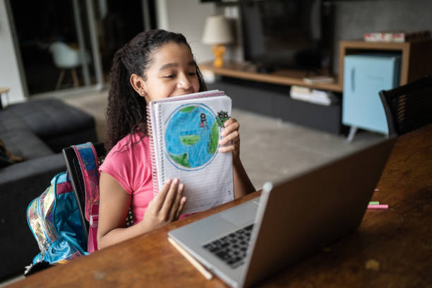 studentessa dedicata che mostra il suo pianeta terra disegnare durante la lezione video a casa - learning child education globe foto e immagini stock