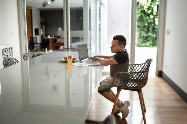 Young man with dwarfism doing home finances during breakfast Young man with dwarfism doing home finances during breakfast dwarf stock pictures, royalty-free photos & images