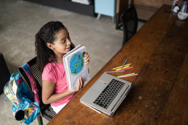 istock Dedicated student showing her planet earth drawing during video class at home 1307065855