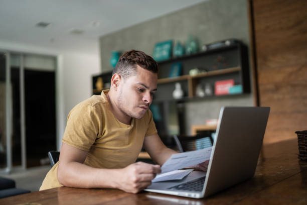 Young man with dwarfism doing home finances Young man with dwarfism doing home finances dwarf stock pictures, royalty-free photos & images