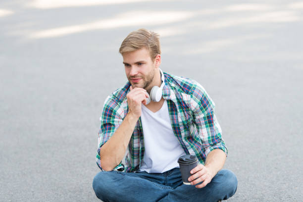 istock Having coffee break. Man sit on ground while drinking coffee. Relax and recharge. Have fun during break. Guy carefree student enjoy coffee outdoors. College life. Life balance. Wellbeing and health 1307066775