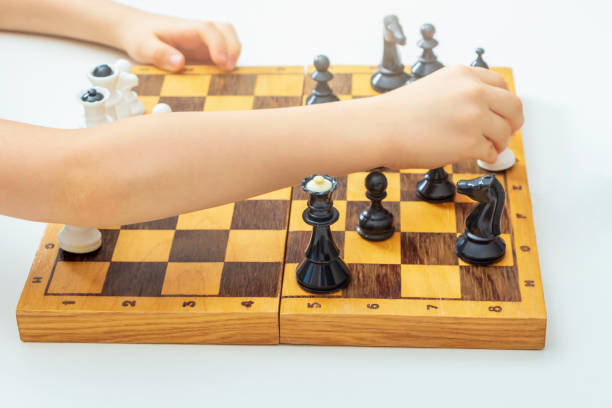 istock Child learns to play chess. Kild's hand holding pawn. 1307067329