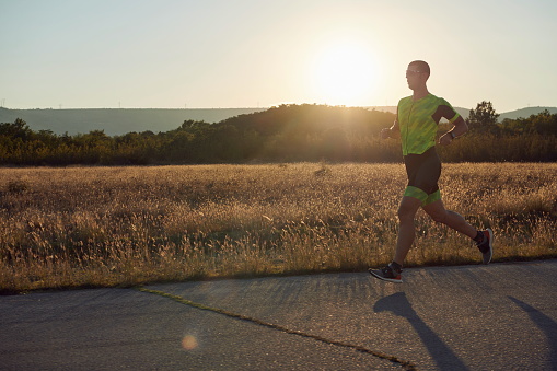 triathlon athlete running on morning training sunrise in the background