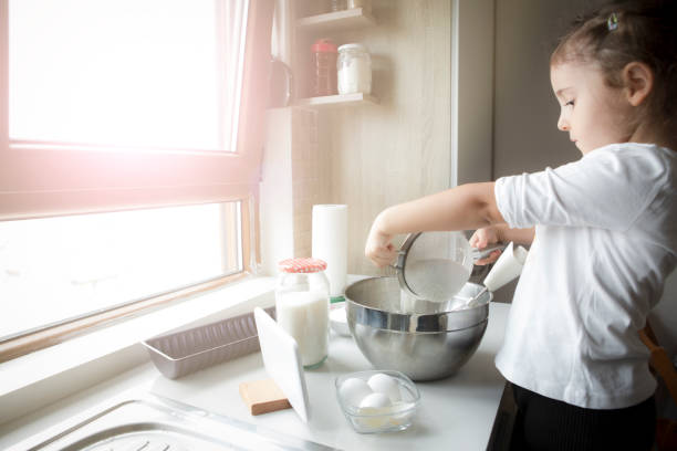 istock Little girl preparing dough for cake in kitchen 1307071231
