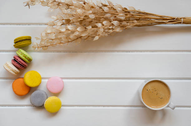 coffee, cake macaron and flower on wood from above.