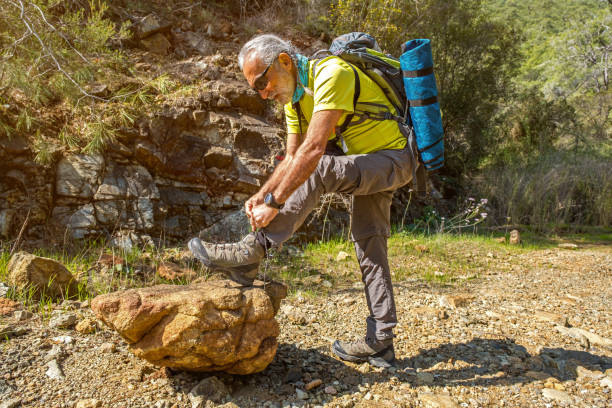 Man with backpack. Tying hiking shoes. Daylight.