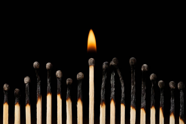 One burning match in line with other black burnt matches