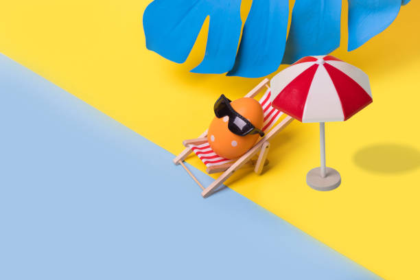 istock Minimal  funny composition with Easter egg with sunglasses sitting on deck chair and sun umbrela on illuminating yellow and bright blue background. 1307075773