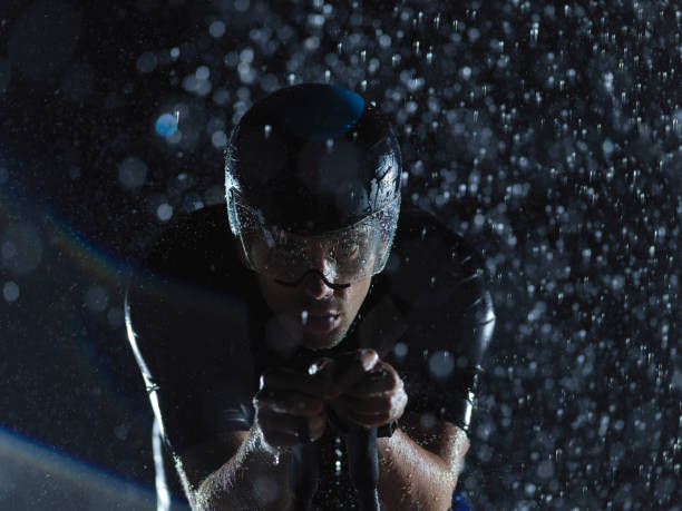 istock triathlon athlete riding bike on rainy night 1307075804