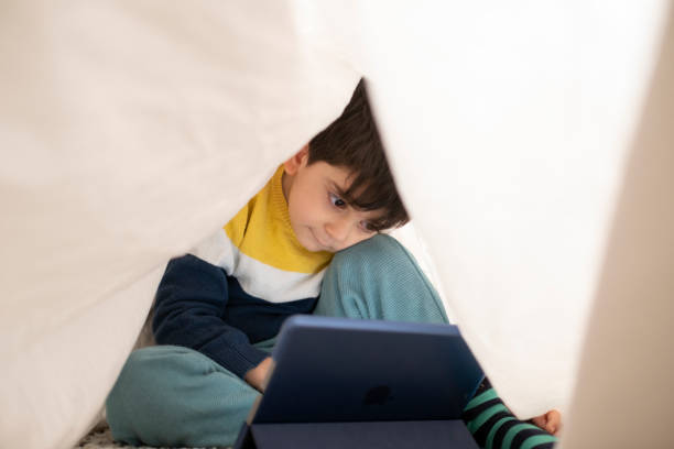 Smiling little boy hiding under sheet