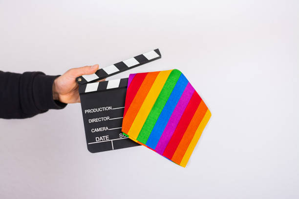 ein mann hand hält eine lgbt regenbogen-flagge und film-klatschbrett - pride lgbtqi veranstaltung stock-fotos und bilder