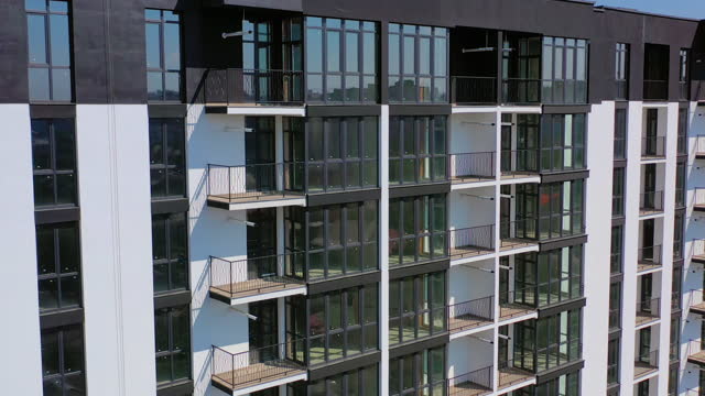 Newly built urban architecture. Exterior of residential building in the city. Modern building with tall glass windows and balconies.