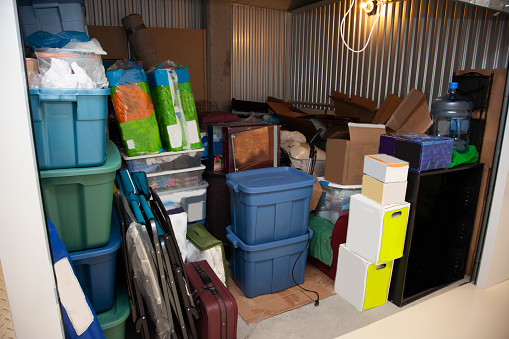 A storage unit full of boxes and plastic tubs