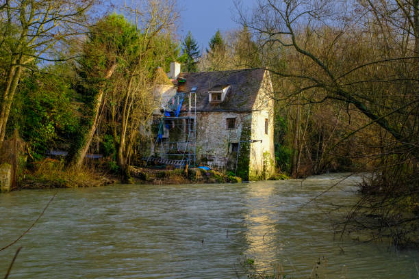 Old watermill wheel on the River Aure at the town of Bayeux in the Normandy region of France. The bridge in the distance is the Pont de la Place aux Pommes.