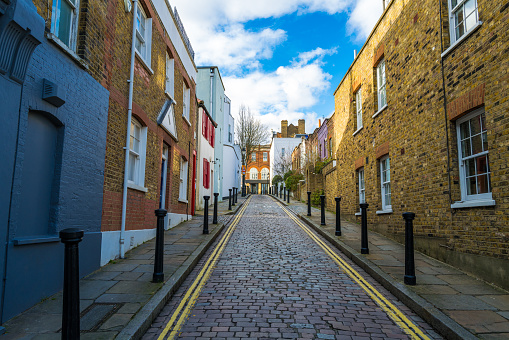 Color image depicting traditional row houses on an old fashioned narrow cobblestone street in Hampstead, London, UK.